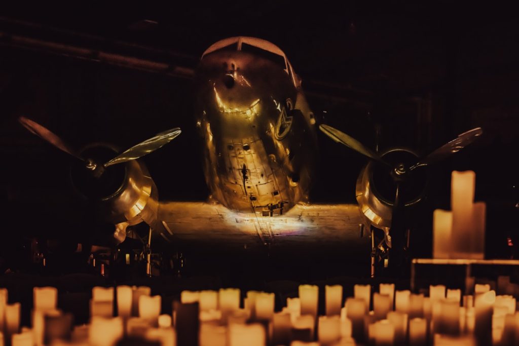 An old aircraft illuminated by hundreds of candles beneath it at Lone Star Museum