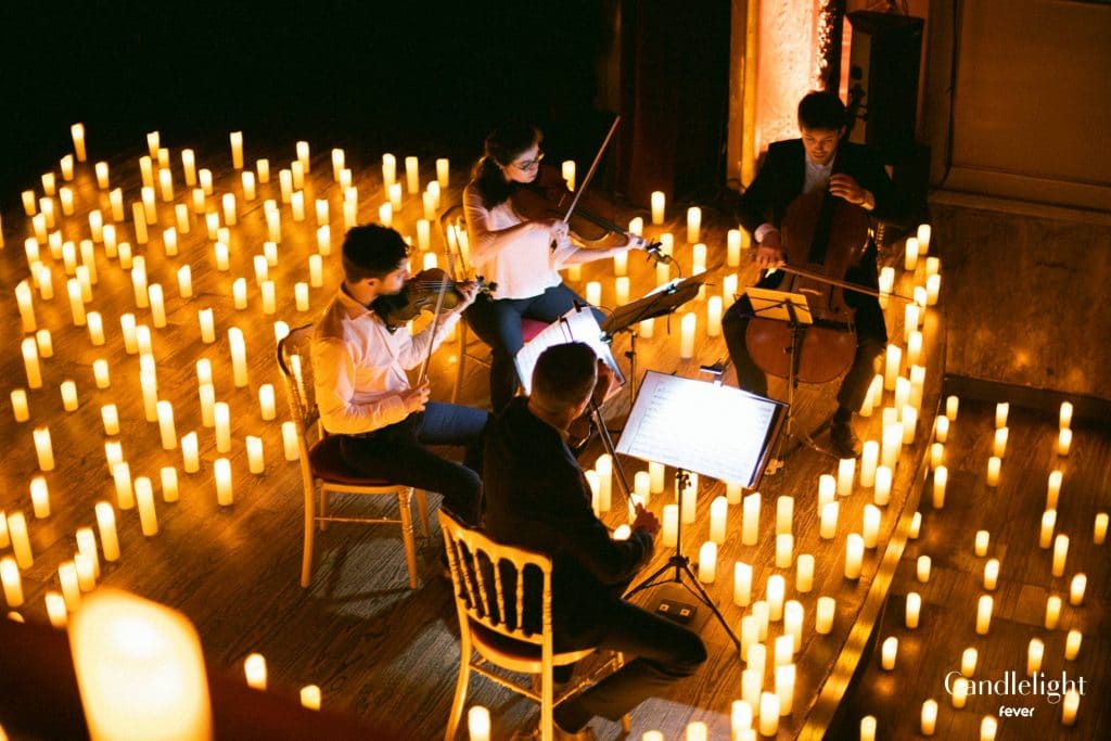 Above shot of a string quartet performing on stage surrounded by a sea of candles