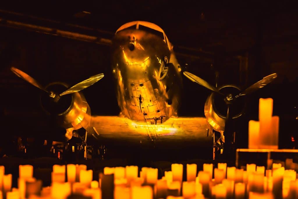 An aircraft on display at the Lone Star Flight Musuem with candles on the ground in front of it.