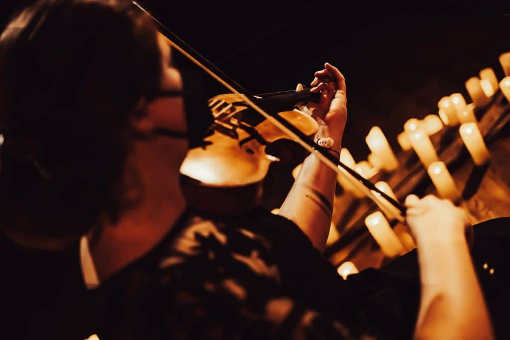 a close-up of a violinist with candles in the background