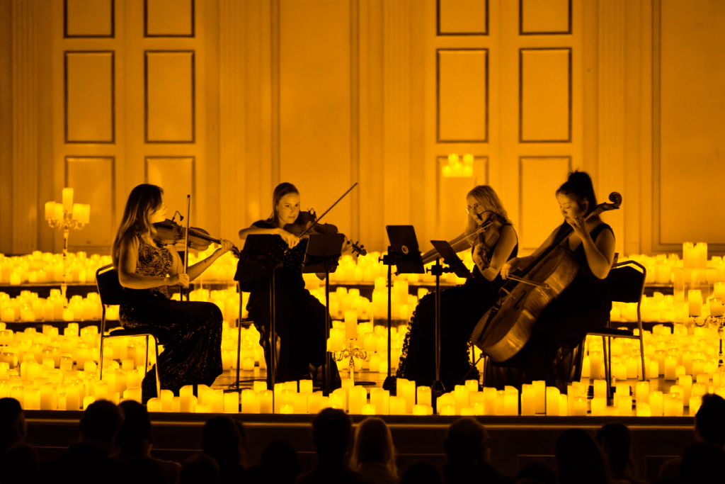 A string quartet performing on a candlelit stage.