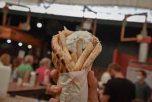 Person holding Greek Gyro with fries inside